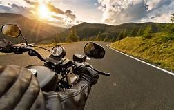 image depicts a motorcycle rider going down a windy mountain road
