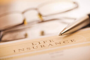 image shows a life insurance document with a pen and eyeglasses